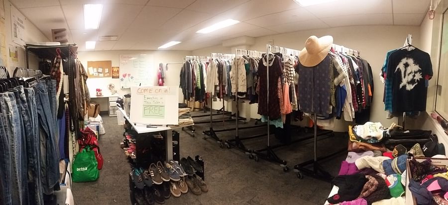 A stylish woman shopping in a thrift store in Atlanta, holding up a vintage dress and smiling.